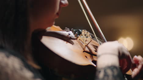 closeup of old violin in hands of woman female musician is playing violin and rehearsing sonata in music hall