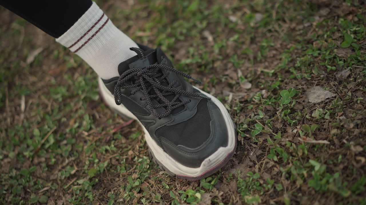 Woman Examines Running Posture, Female Athlete Evaluates Stance And Grip, Caucasian Woman Reviews Sprinting Technique Thoroughly, Woman On Grass Checks Foot Positioning And Running Alignment Carefully