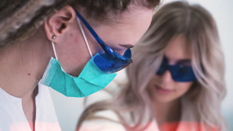 woman in mask and goggles does laser epilation in clinic