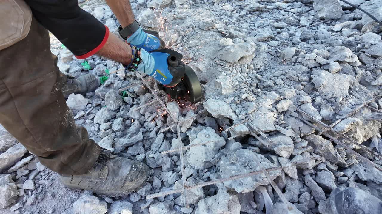 Man cutting steel fiber-reinforced concrete's construction iron with a round iron cutting machine,sparks over debris.