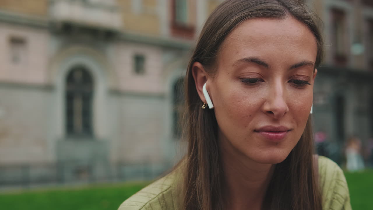 Mujer joven disfrutando de la música con auriculares inalámbricos al aire libre.