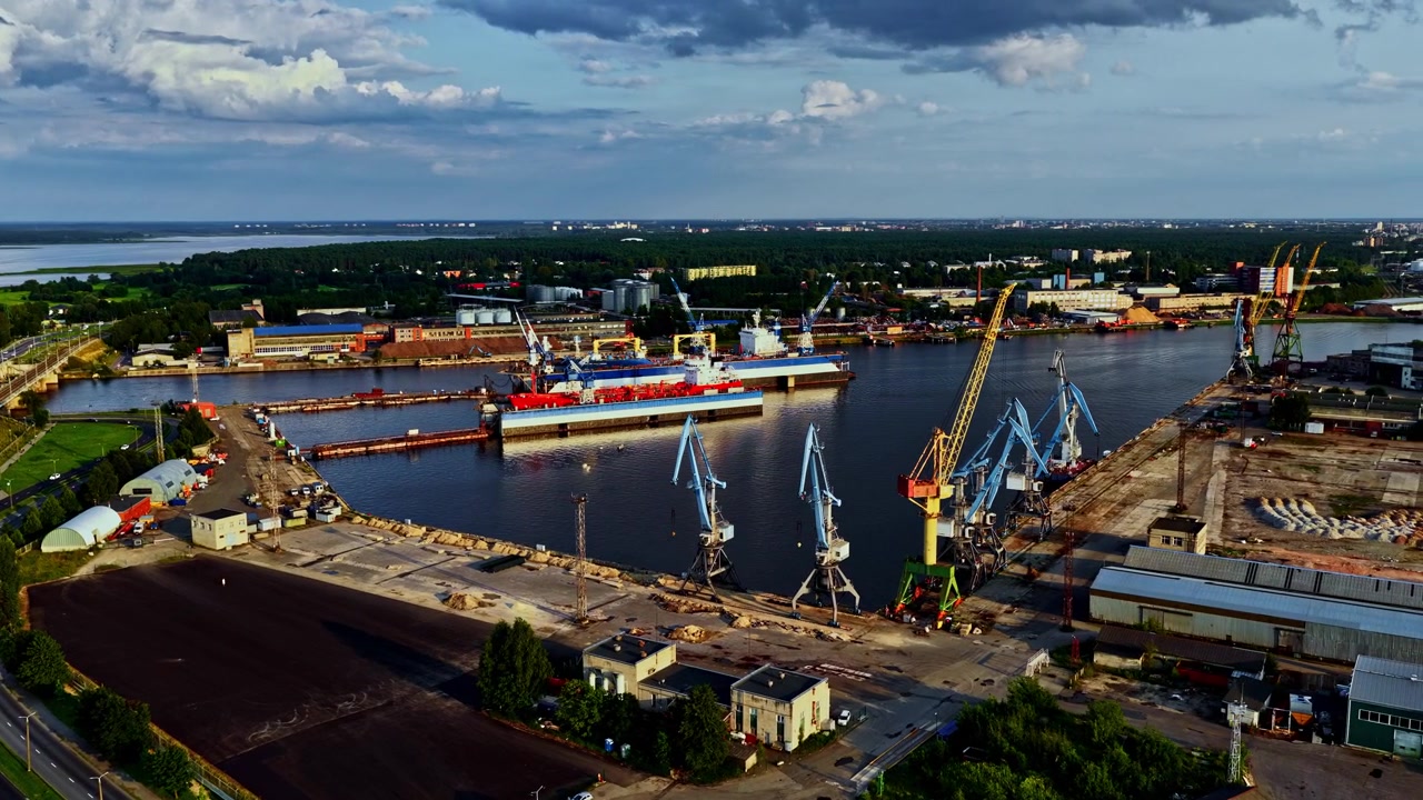Pemandangan luas pelabuhan industri dengan derek biru dan dermaga kapal.