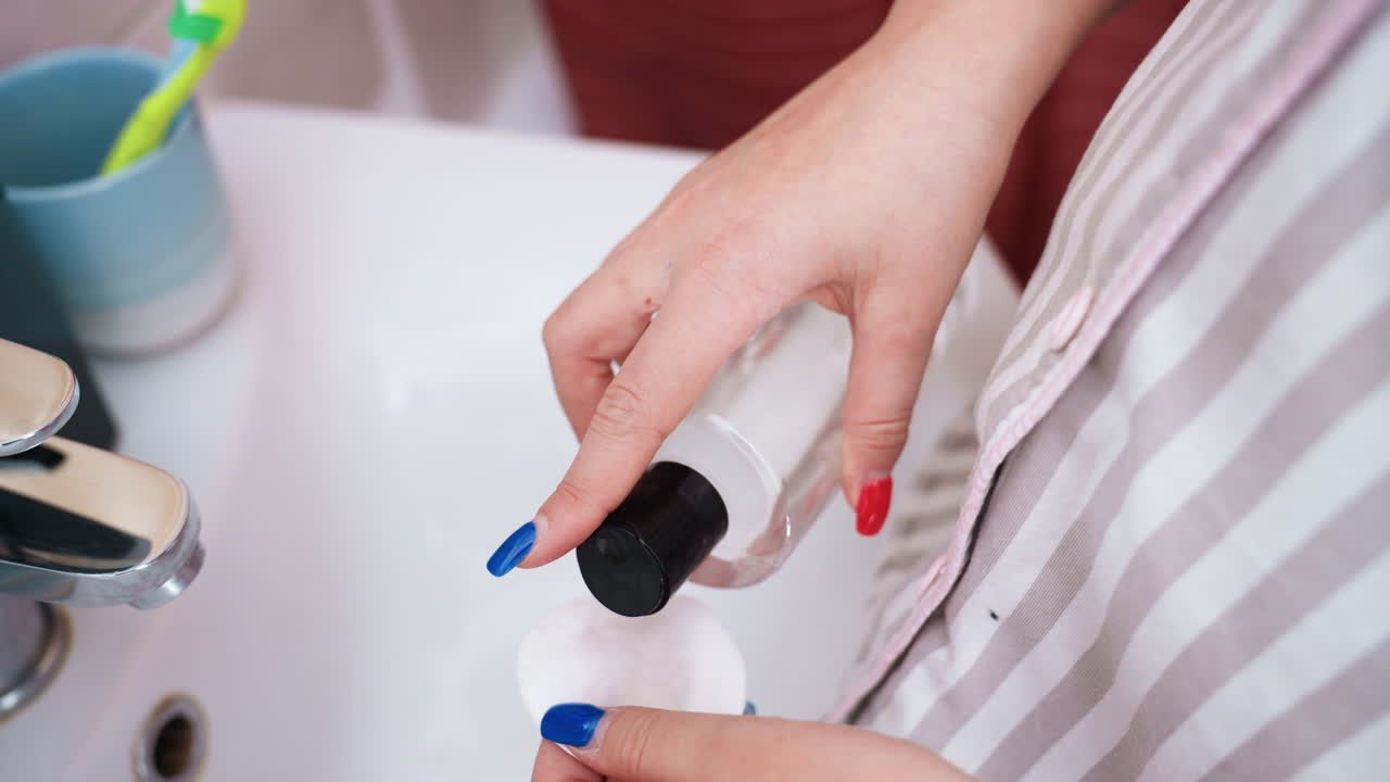 Person Delicately Applies Face Wash, Woman Dispenses Transparent Liquid Onto Cotton At Bathroom Sink, Person Gently Spreads Facial Cleansing Liquid On Cotton Wool In Bathroom Setting