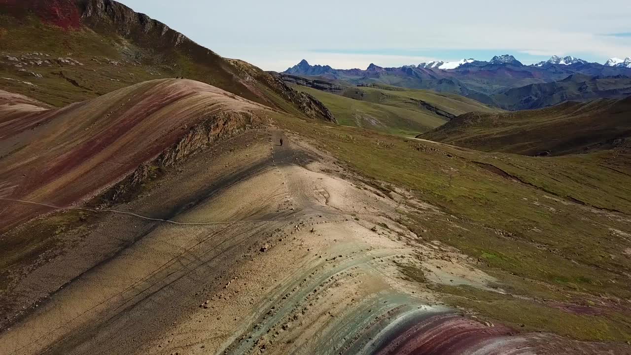 Aerial, pan, drone shot around a hiker walking on the Palcoyo rainbow mountain, in Valle Rojo, sunny day, in Andes, Peru, South America