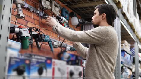 man looking at power tools in a hardware store