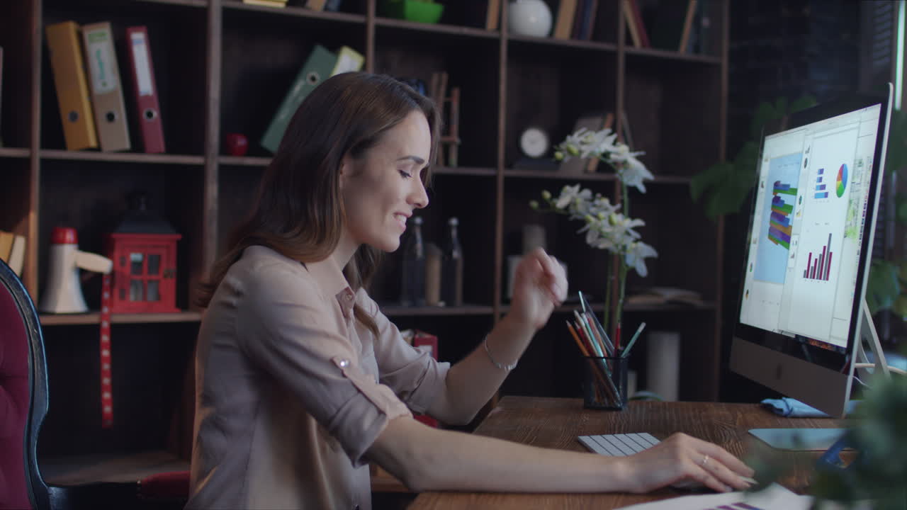 Donna d'affari di successo che osserva grafici e diagrammi sullo schermo del computer.