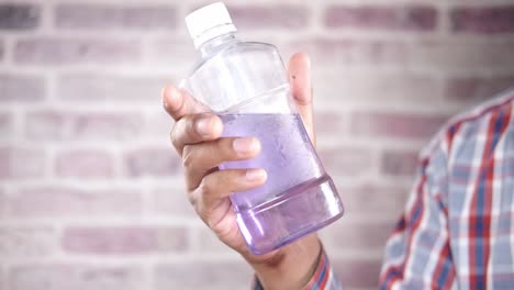 person holding a purple liquid bottle