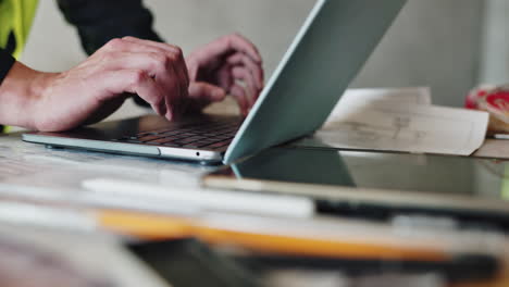 construction worker using laptop and plans