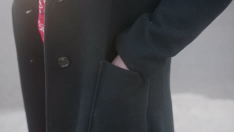Close-up-of-a-woman-putting-her-left-hand-in-her-elegant-black-coat-pocket