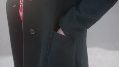 close up of a woman putting her left hand in her elegant black coat pocket