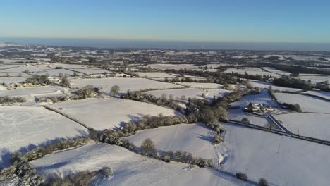 frío invierno nevado británico patchwork tierras de cultivo campo rural escena aérea al amanecer cinemático pan derecha