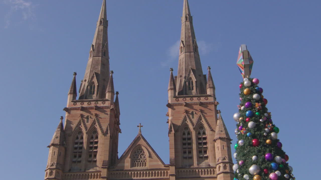 Pan up Cathederal in Sydney with a well decorated Christmas tree infront.