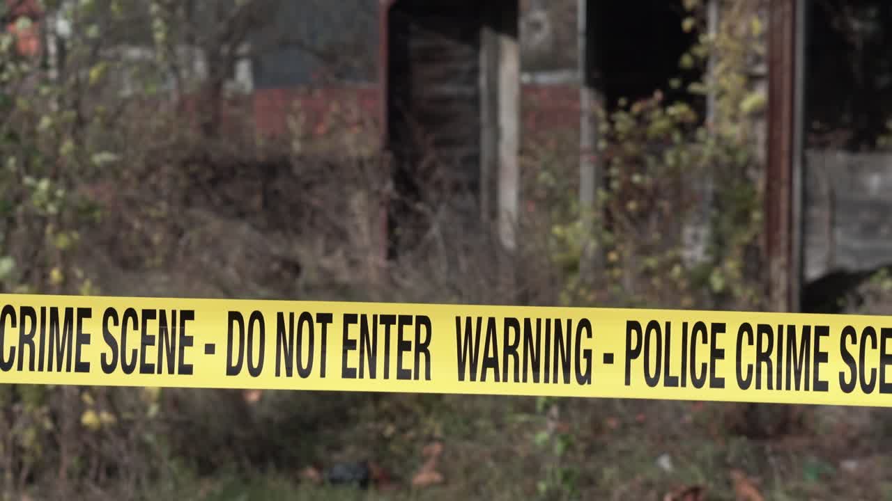 Police Crime Scene Tape in Front of Old Rustic Building and Overgrown Yard