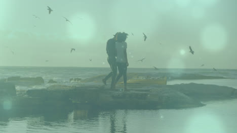 Animation-of-light-spots-over-biracial-couple-at-beach