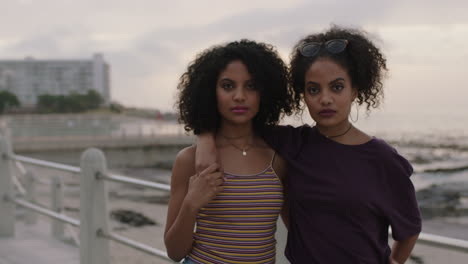 portrait of attractive hispanic twin sisters embrace posing looking confident to camera