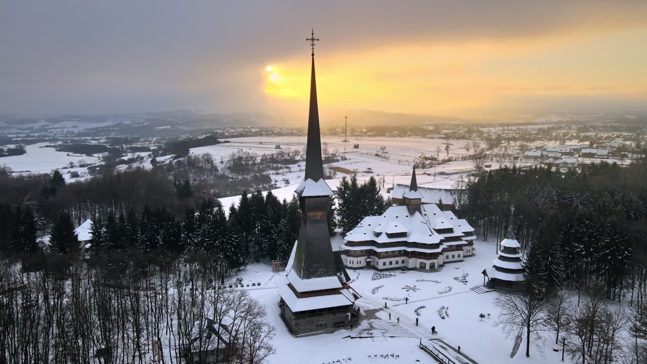 Letecký pohled dronem na klášter Peri-Sapanta v zimě, Rumunsko. Hlavní kostel a budova, návštěvníci, holý les a sníh v okolí.