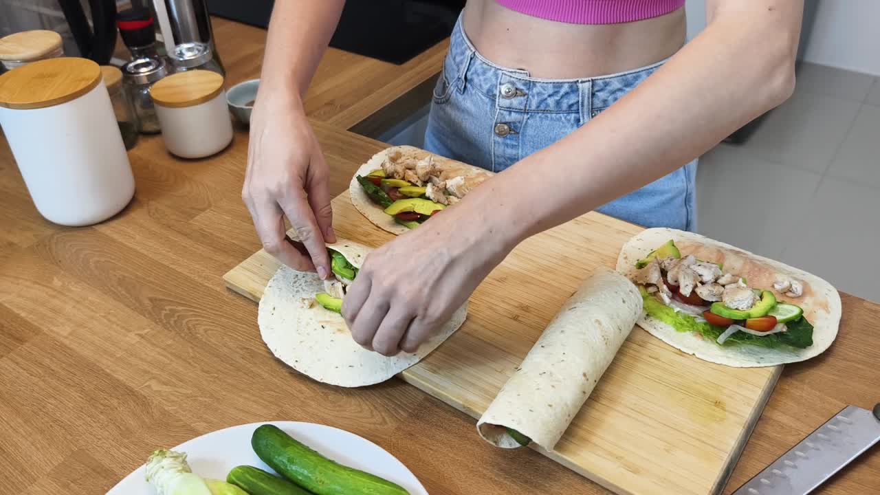 mujer haciendo envolturas de pollo y aguacate