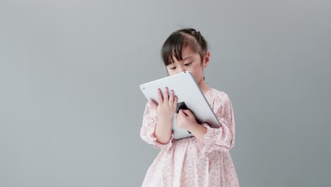 Child-watching-cartoon-with-digital-tablet-in-studio-with-gray-background