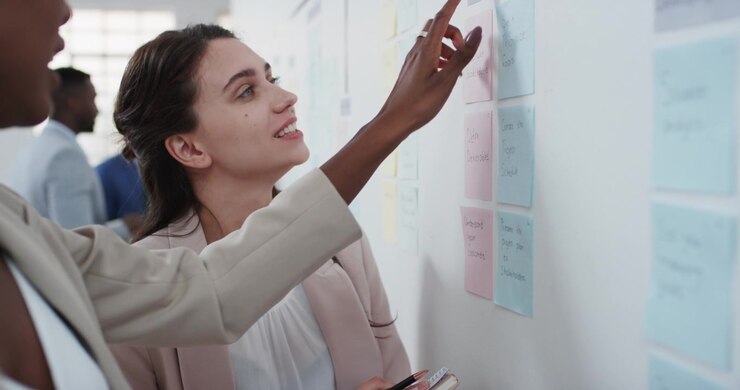 Businesswomen Collaborating on Project Strategy Using Sticky Notes in Office