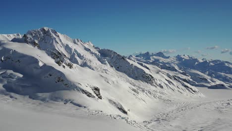 Aerial-drone-shot-flying-over-massive-icefield-with-mountains-in-distance