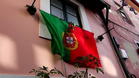 Primer-Plano-De-Una-Gran-Bandera-Portuguesa-Colgada-De-La-Ventana-De-Una-Casa-En-Oporto,-Portugal