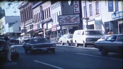 cars driving down main street of a small city