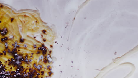 partículas de tinta coloridas en aceite se fusionan en un líquido blanco lechoso, abstracto
