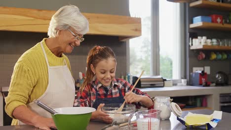 Grandmother-watching-the-girl-happily-while-mixing-flour-4K-4k