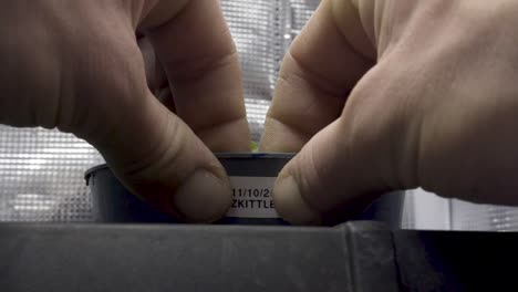 gardener putting label with date and name of pant on flower pot - growing zkittlez cannabis - fast forward shot