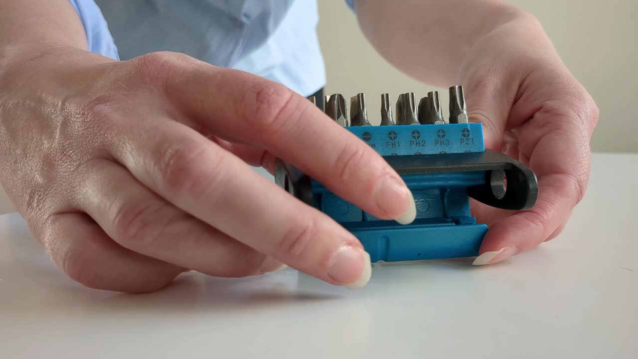 Woman opening screwdriver bit set and choosing right bit, close-up