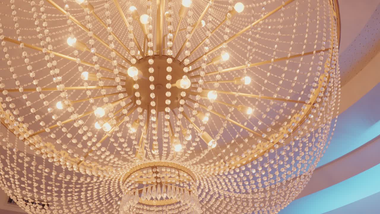 Luxurious chandelier with golden frame and crystal beads shining in warm light