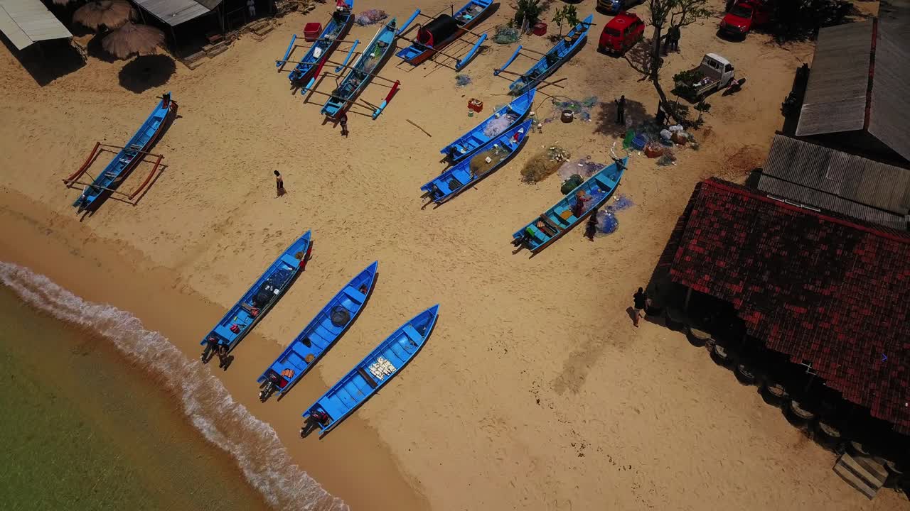 화창한 날 인도네시아의 모래 해변에 주차된 파란색 어선의 공중 전망