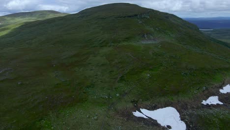 Aufnahmen-Von-Rückwärtsdrohnen,-Die-Einen-Schwedischen-Berggipfel-Mit-Wanderern-Zeigen,-Während-Mitten-Im-Sommer-Schnee-Freigelegt-Wird