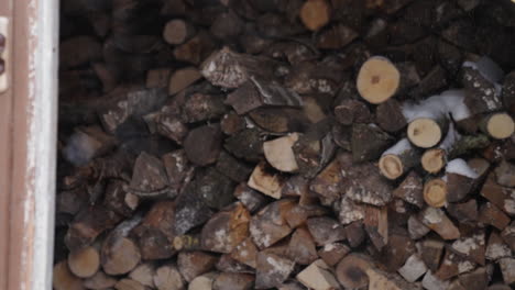 cinematic-firewood-stacks-of-wood,-snowflakes-falling,-a-view-of-huge-stacks-of-logs,-Rural-winter-life