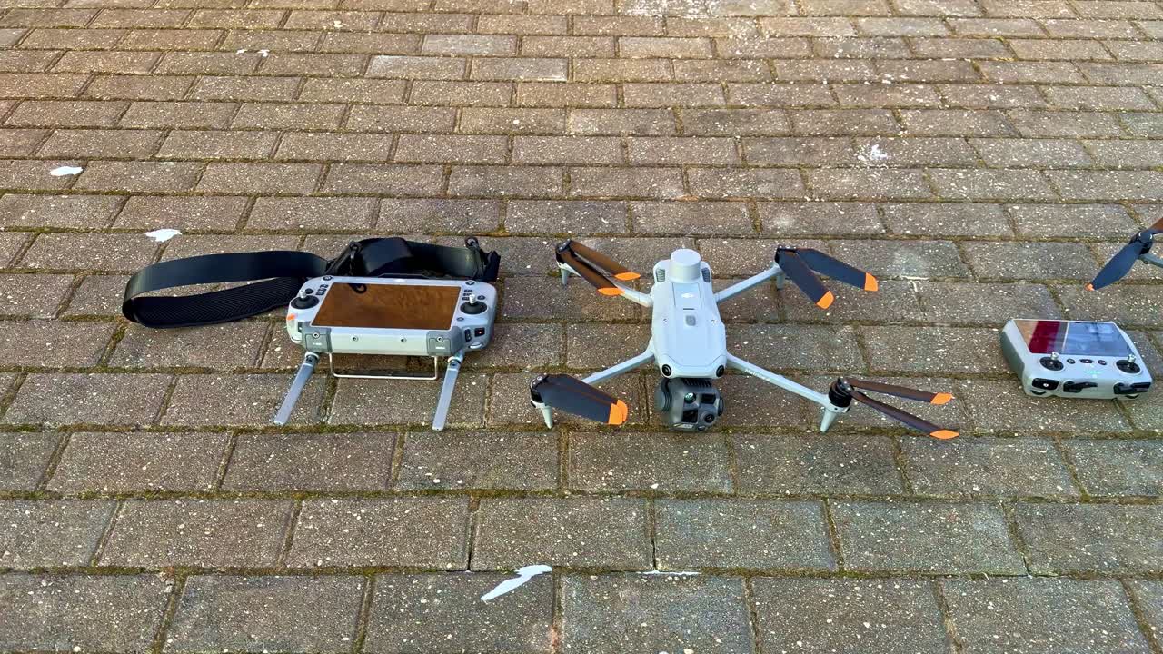 Kaksi dronea ja kauko-ohjainta aseteltuna jalkakäytävälle