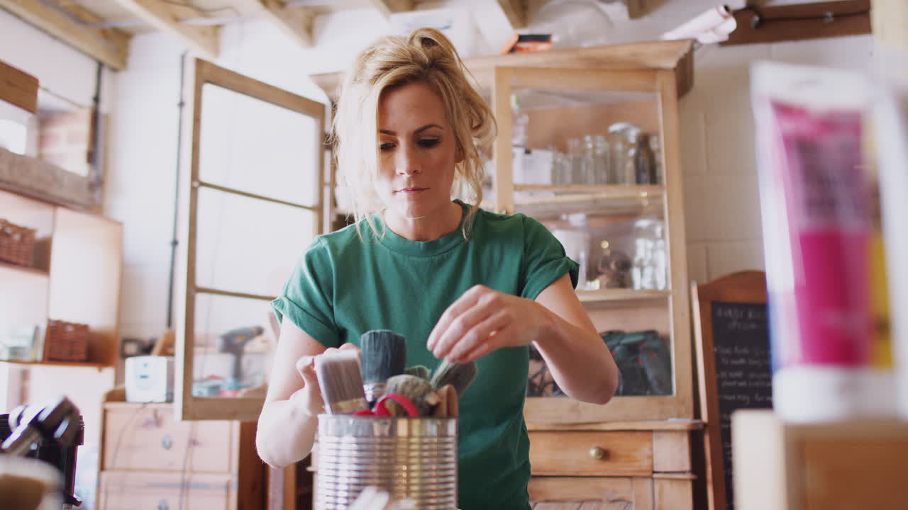 mulher na oficina a escolher pincel para projetos de reciclagem e artesanato