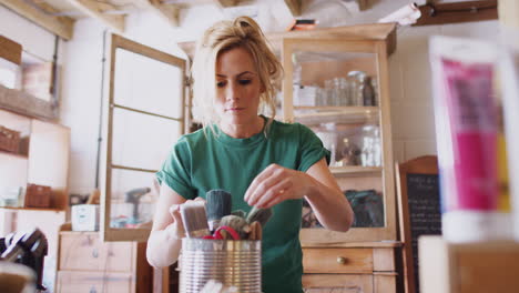 woman in workshop choosing paintbrush for upcycling and  craft projects