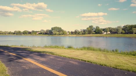 bike trail in foreground with a lake in the background under a sky of white puffy clouds