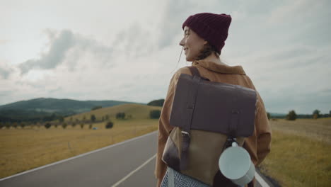 female tourist with backpack walking on road