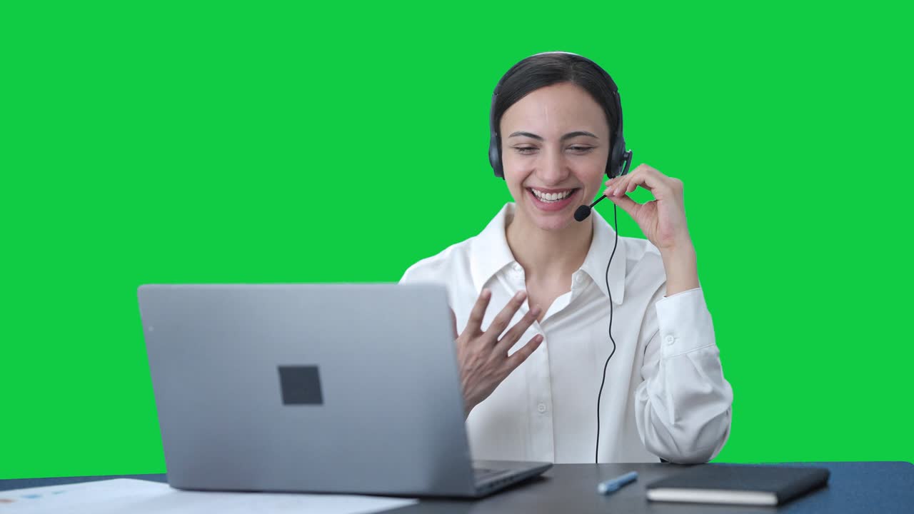 Operatrice indiana felice del call center che parla con il cliente, schermo verde.