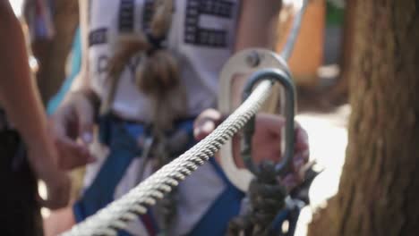 mujer joven en cinturón de seguridad para el montañismo tomando carabina en la escalada par