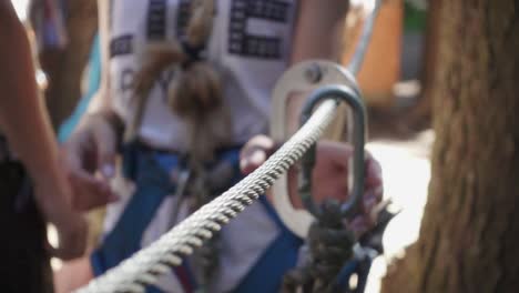 young woman in security belt for mountaineering taking carbine in climbing par