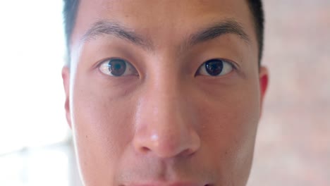 close up portrait of asian creative businessman opening eyes and smiling in office, slow motion