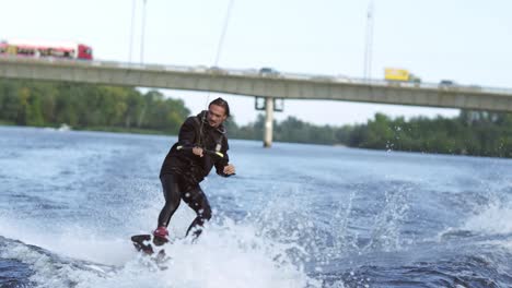 joyful man wakeboarding on city river. extreme entertainment on water