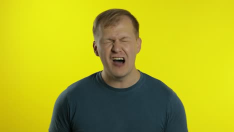 portrait of young caucasian man posing in green t-shirt. shocked guy screams, shakes head, says no