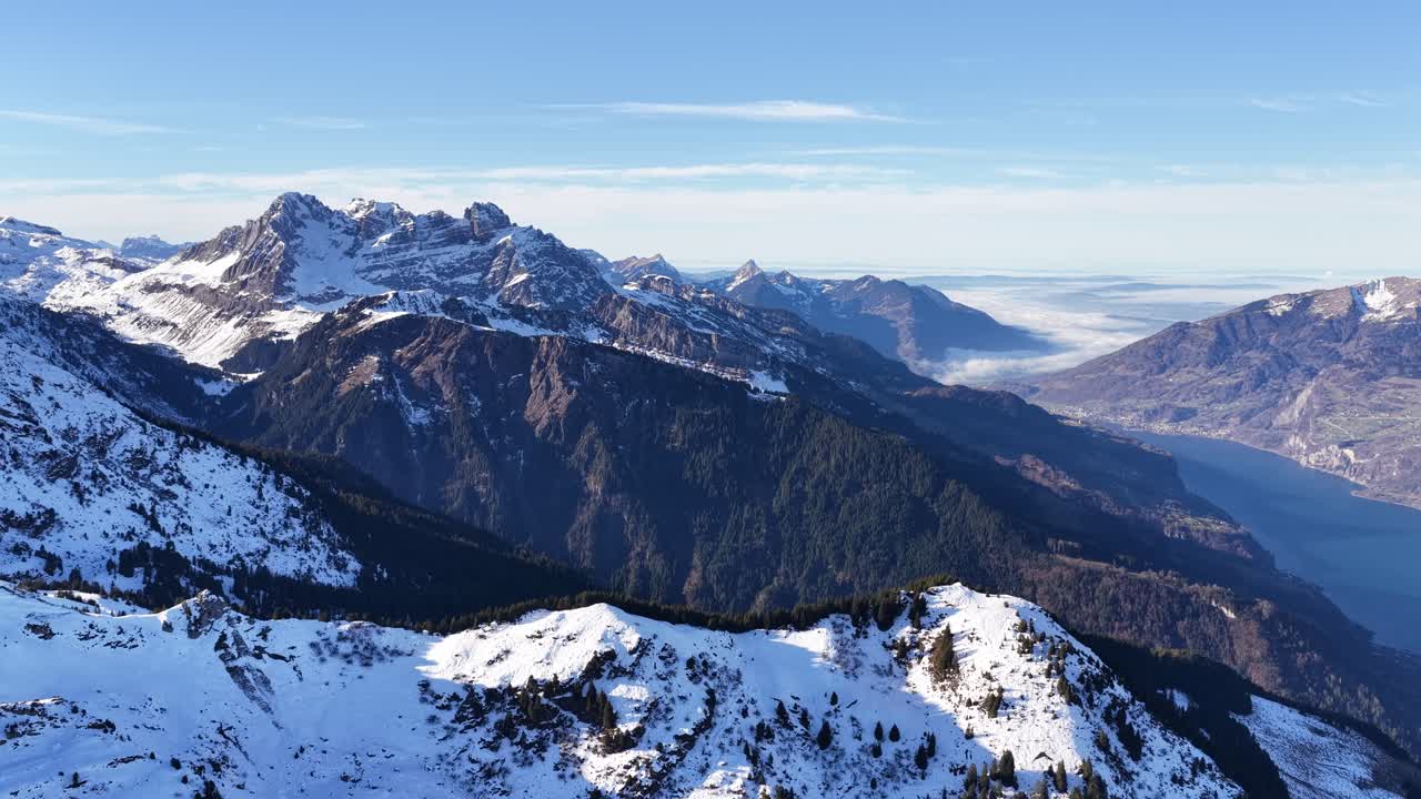 Churfirsten mountain range overlooking Walensee near Flumserberg, Switzerland with snow-covered alpine peaks, deep valley, clear sky and winter landscape view from aerial drone