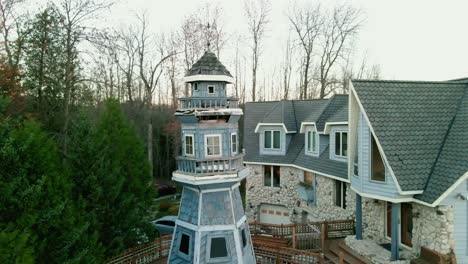 antena cinematográfica que orbita alrededor de una gran mansión azul con un faro privado rodeado de árboles verdes en wisconsin, ee.uu.