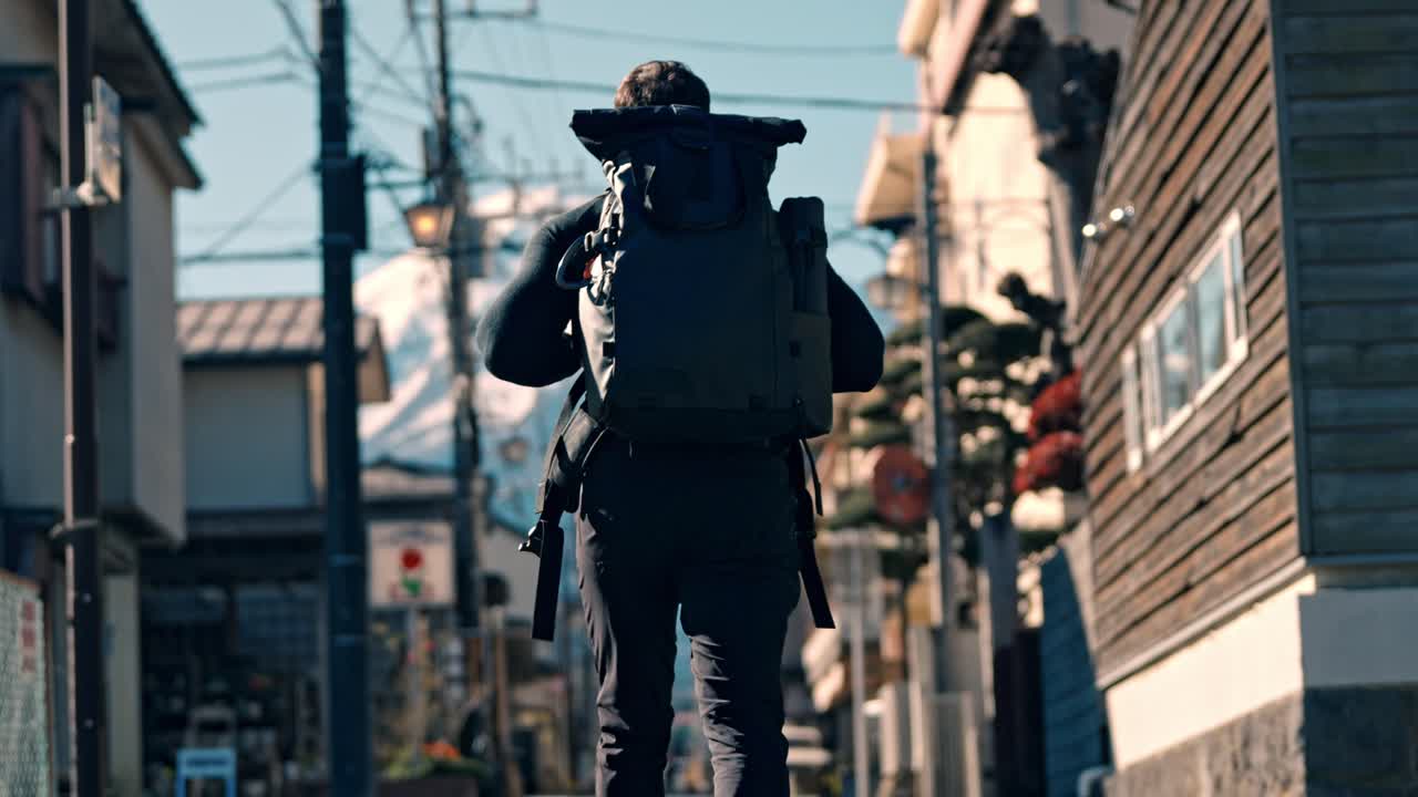 A cinematic video clip showcasing a man walking along a Street in Shizuoka City, with the iconic snow-covered Mount Fuji towering in the background.