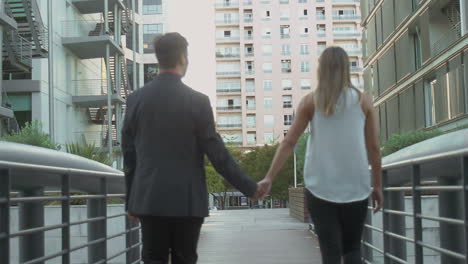 young couple holding hands on urban city street