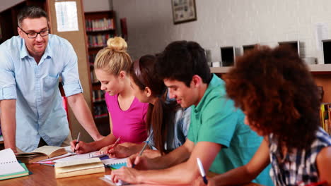 Jóvenes-Estudiantes-Revisando-En-La-Biblioteca-Con-Su-Profesor.